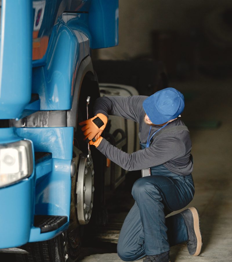 A young worker checks wheel. Truck malfunction. Service work.